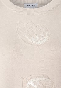 Cremefarbener Pullover mit Rundhalsausschnitt, verziert mit gestickten Blattmotiven und Pailletten für zusätzliche Textur. Das Etikett trägt die Aufschrift "MORE & MORE."