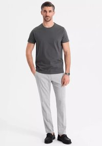 Grå kortærmet t-shirt parret med lysegrå bukser og sorte sko; har et simpelt, rent design og en skræddersyet pasform.