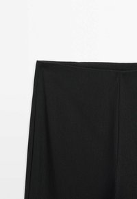 Jupe noire droite avec taille haute et détails simples de couture sur fond blanc uni.