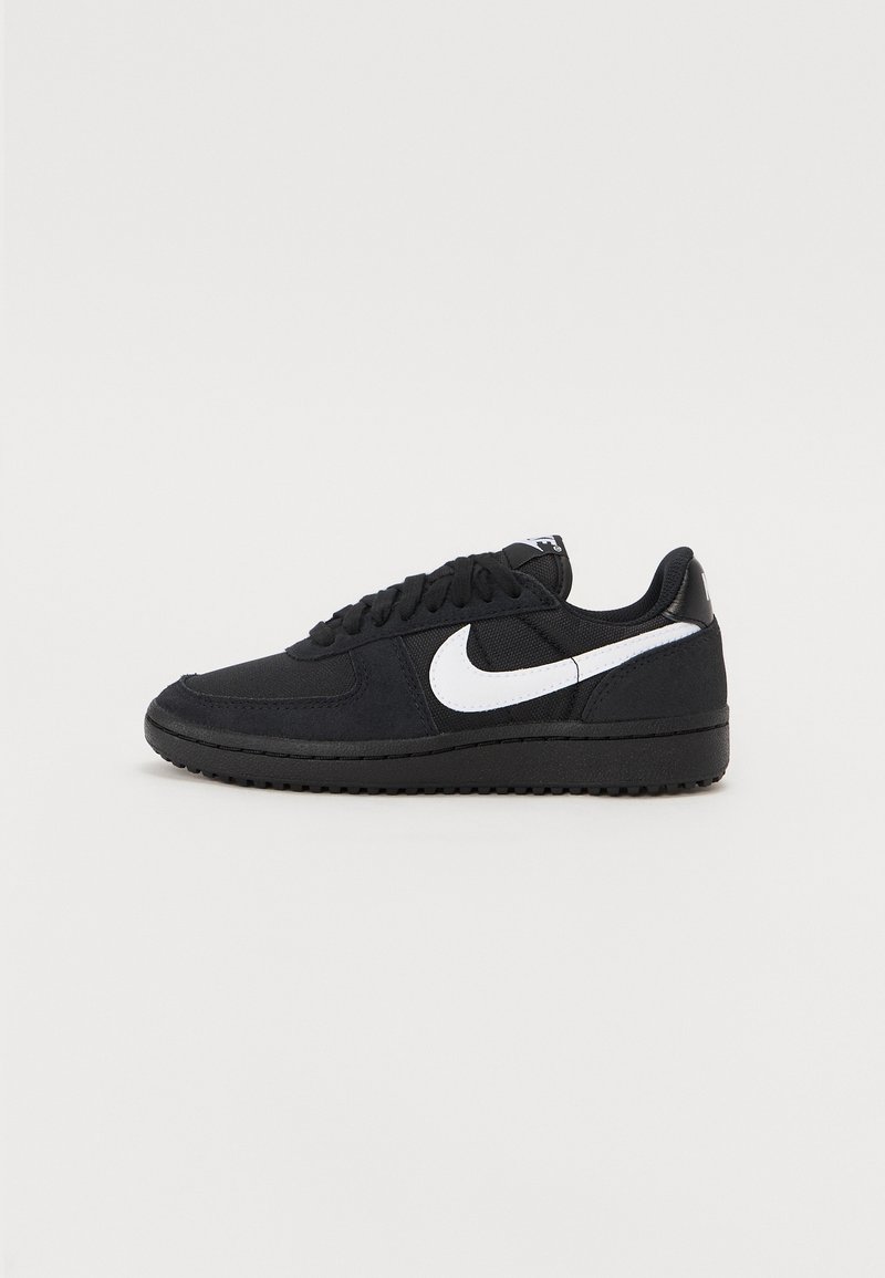 Baskets noires Nike avec logo swoosh blanc, design à lacets et semelle texturée, montrées de profil sur un fond uni.