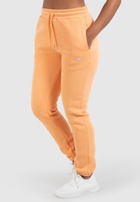 Orange sweatpants med snoreliv, sidelommer og en lille logoaccent. Blødt stof og tætsiddende ankler.