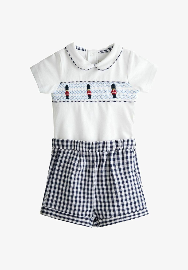 Weißer Baby-Strampler mit bestickten königlichen Wachen, Peter-Pan-Kragen und angenähten Shorts in marineblauem Vichy-Karo.