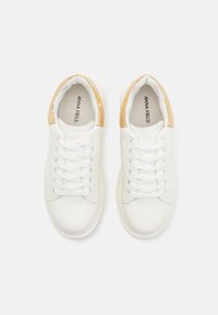 Hvite syntetiske sneakers med glatt overflate, med en beige hælakkent. Sjølvskene er hvite, og innsiden er foret med myk stoff.