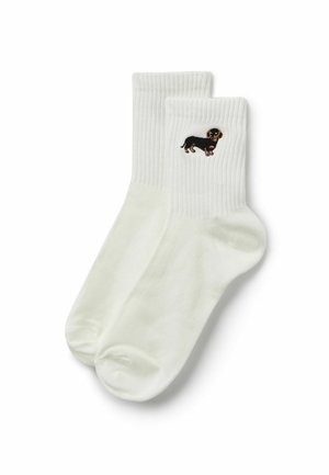 Paar weiße Crew-Socken mit einem kleinen schwarzen und braunen Dackel auf dem gerippten Bündchen, der gestickt ist.