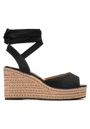 Sandalia de cuña negra con punta abierta, parte superior de tela y plataforma de yute trenzado. Correa ajustable de tela negra en el tobillo para un ajuste seguro.