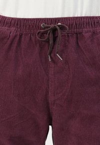 Bordeaux corduroy broeken met een gestructureerd oppervlak, elastische tailleband en koordje voor een verstelbare pasvorm. Heeft zijzakken.