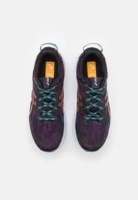 Chaussures de sport noires et violettes avec un dessus texturé, lacets turquoise, accents réfléchissants et une semelle extérieure blanche. Logo orange sur les semelles intérieures.