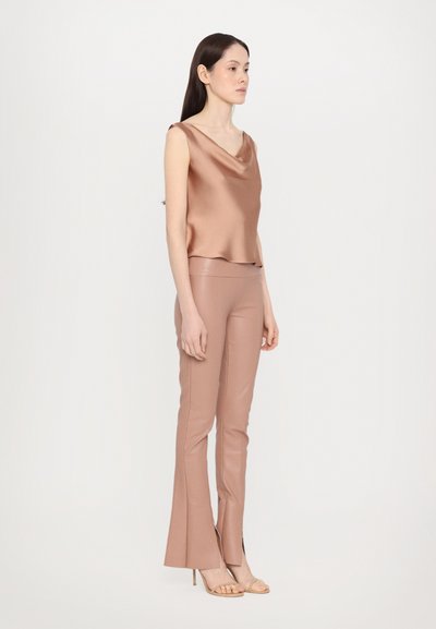 Cowl neck satin top and fitted, flared pants in a soft, rosy beige. Textured fabric with side slits at the hemline. Simple sandals complete the look.