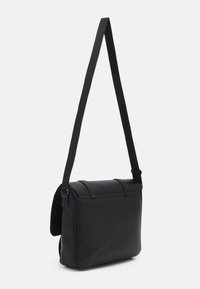 Sacoche en cuir noir avec bandoulière réglable, fermeture à rabat rectangulaire et design minimaliste épuré.