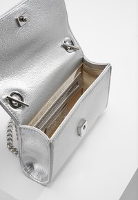 Borsa a mano argentata con texture, dotata di tracolla a catena, chiusura magnetica, scomparti interni per carte e una fodera liscia di colore chiaro.