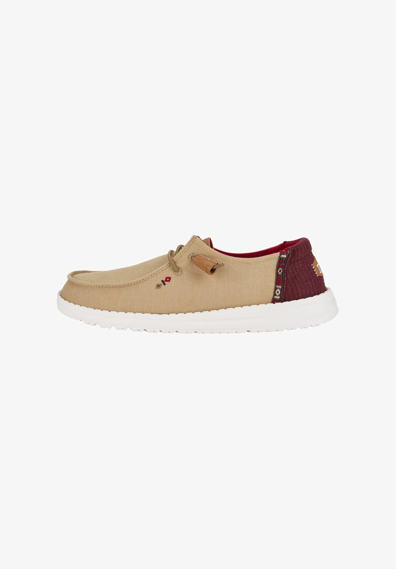 Botte en toile à enfiler beige avec des accents bordeaux, dessus texturé, semelle blanche et couture décorative. Comprend un détail de lacets.