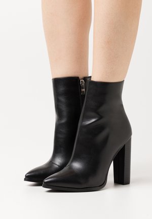 Schwarze Ankle Boots aus glattem Leder mit einer spitzen Zehenpartie, einem seitlichen Reißverschluss und einem strukturierten Blockabsatz.