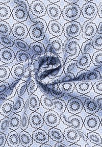 Tessuto di cotone con un motivo floreale blu e bianco con contorni neri, che presenta una texture liscia e una piega a spirale.