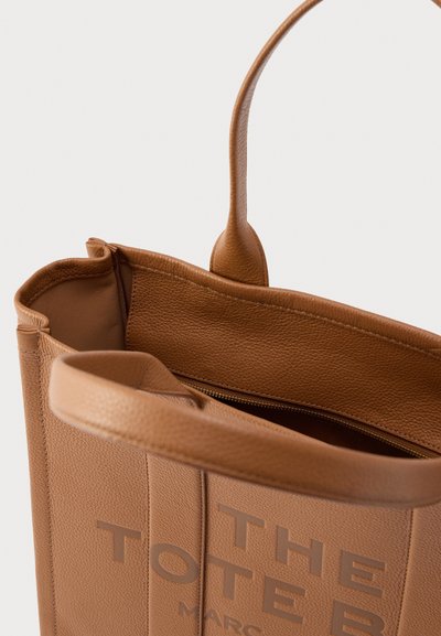 Geantă tote din piele maro cu finisaj texturat, interior cu fermoar și text în relief pe lateral. Dispune de două mânere robuste.