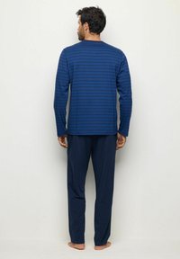 Långärmad, marinblå pyjamaströja med horisontella ränder, parat med matchande enfärgade marinblå byxor. Mjuk kvalitet och avslappnad passform.