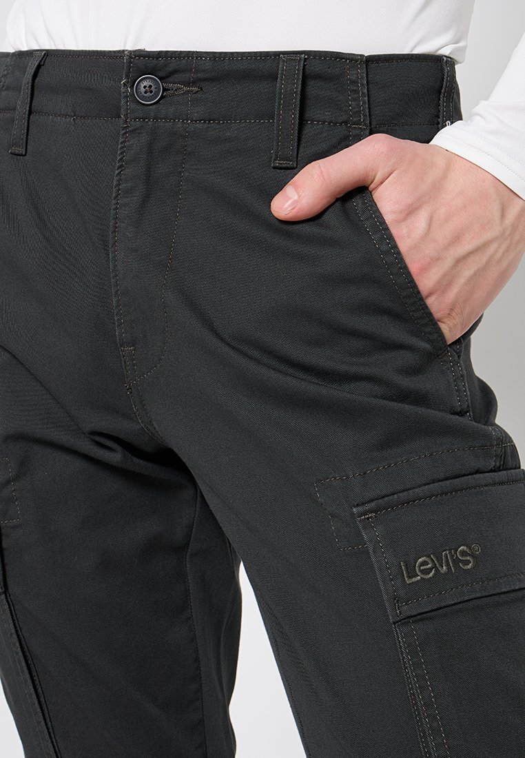Pantalones cargo de color carbón con detalles cosidos, múltiples bolsillos y un logo de Levi's en el lateral. Hechos de una tela duradera, diseñados para la utilidad.