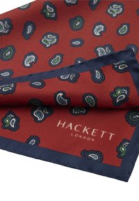 Punainen silkki taskuliina, jossa on sinisiä paisley-kuvioita ja tummansininen reunus, jonka alakulmassa on valkoinen "Hackett London" -logo.