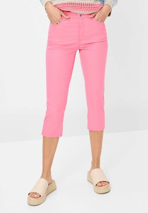 Pantalons courts rose pâle en tissu extensible, dotés de passants de ceinture et de poches avant, associés à des sandales à plateforme beiges.