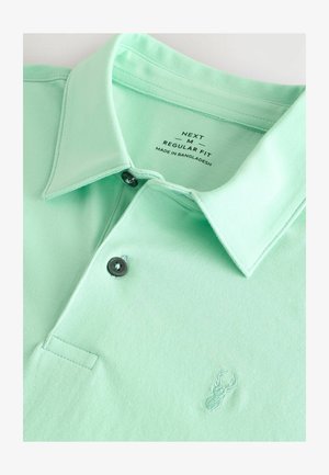 Polo mint vert avec un col classique, patte de boutonnage à deux boutons, boutons noirs et un petit logo de homard brodé sur la poitrine.