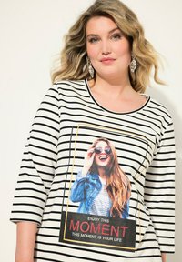 Dreiviertelarm-Shirt mit schwarz-weißen Streifen, das einen großen grafischen Druck einer Frau mit Sonnenbrille zeigt. Weicher Stoff.