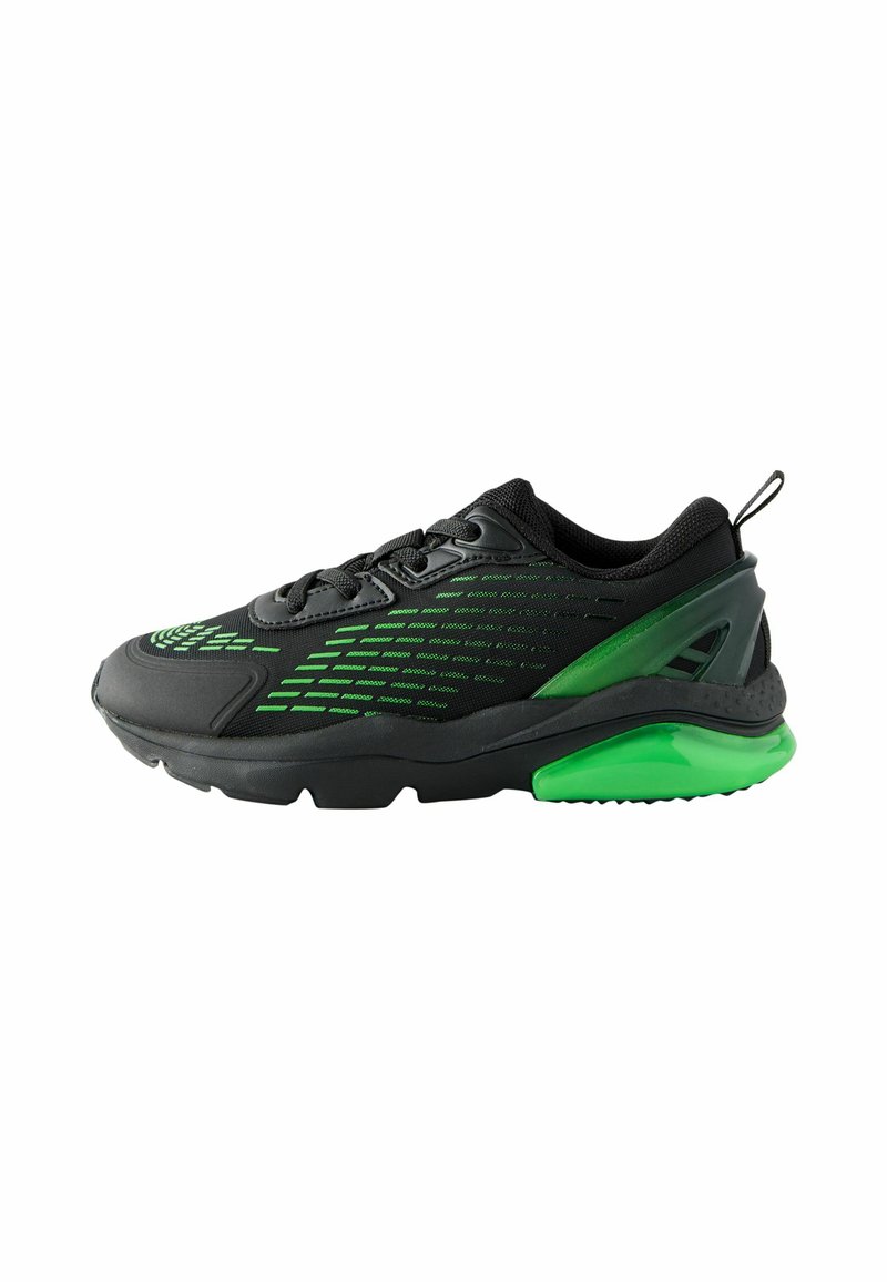 Zapatilla de correr negra con acentos verdes, parte superior de malla y sintético, suela texturizada, cuello acolchado y diseño distintivo en el talón.