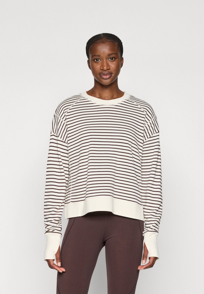 Long-sleeve striped top in cream and brown. Features a relaxed fit, round neckline, and ribbed sleeves with thumbholes.