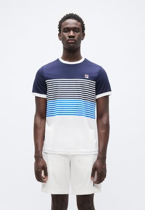 Marineblauw T-shirt met korte mouwen en witte en blauwe horizontale strepen, witte onderkant, met een Fila-logo op de linkerborst. Draagt witte shorts.