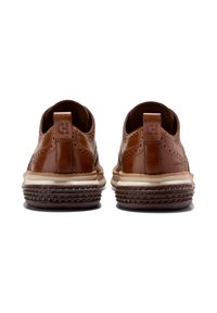 Scarpe in pelle marrone caratterizzate da un motivo testurizzato, con retro arrotondato e suola in gomma con design geometrici. Presentano un piccolo logo sul tallone.