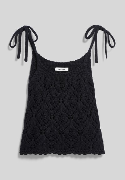 Schwarzes, ärmelloses Strickoberteil mit Diamant-Spitzendesign und Bindebändern vor schlichtem grauem Hintergrund, mit "IVY OAK" Etikett im Halsausschnitt.