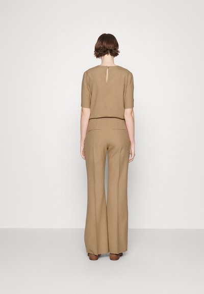 Pruun, linasegu top lühikeste varrukatega ja tagumise võtmeauguga detail, kombineeritud kõrge vöökohaga flared pükstega samas värvitoonis.