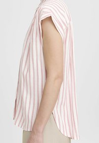 Blusa de manga corta en tejido ligero, con rayas verticales rojas sobre fondo blanco; dobladillo redondeado con aberturas laterales.