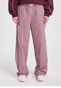 Red and white striped wide-leg pants with a relaxed fit, featuring an elastic waistband and two buttons at the front. Smooth fabric texture.