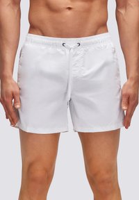 Pantaloni da bagno bianchi realizzati in materiale leggero, dotati di vita elastica con cordoncino e design semplice e raffinato.
