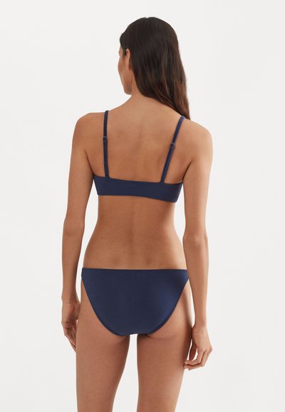 Navy blue bikini-setti, jossa on ohut olkaimeton rintaliivimalli ja klassiset hipster-pohjat. Sujuva tekstuuri ja minimaalinen ommelluista yksityiskohdista.