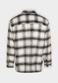 Chemise en flanelle à carreaux noirs et blancs, dotée d'un col à revers, de manches longues et de poignets à boutons. Tissu texturé avec une finition douce.