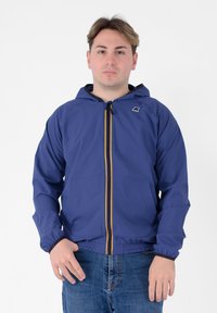 Giacca a cappuccio blu navy con zip frontale, caratterizzata da una striscia colorata e polsini elasticizzati. Il materiale appare leggero e liscio.
