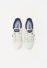 Hvite sneakers med marineblå detaljer, gullhull og en såle av minneskum. Har "Wrangler" logo på tungen og siden. Størrelse 42.