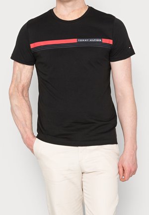 Schwarzes T-Shirt mit kurzen Ärmeln und rundem Halsausschnitt, mit einem horizontalen roten und marineblauen Streifen, gebrandetem Logo und glattem Baumwollmaterial.
