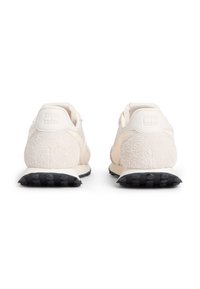 Άσπρα αθλητικά παπούτσια με μαλακή, υφασμάτινη πίσω επιφάνεια, μαύρη λαστιχένια σόλα και επενδυμένο κολάρο. Απλός σχεδιασμός με μοντέρνες λεπτομέρειες.