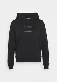 Sudadera con capucha negra, con bolsillo frontal y un logotipo cuadrado enmarcado en dorado que presenta el texto "Tommy Jeans" en el pecho.