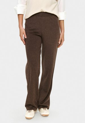 Pantaloni marroni a gamba larga realizzati in un tessuto morbido, con vita elasticizzata e vestibilità rilassata, abbinati a sneaker di colore chiaro.
