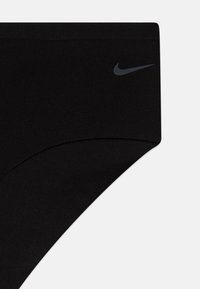 Črne Nike spodnjice z gladko teksturo in modernim dizajnom. Z discreetnim sivim logotipom na levi strani. Preprost in minimalističen oblik.