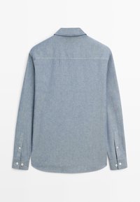 Světle modrá košile s dlouhým rukávem a límečkem, zapnutá na knoflíky, zobrazená zezadu na jednobarevném bílém pozadí.