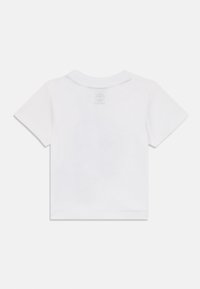 Valkoinen puuvillainen t-paita, jossa on lyhyet hihat, pyöreä pääntie ja hillitty logo selän niskan kohdalla. Sileä pinta.