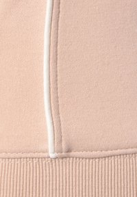 Tessuto di felpa rosa chiaro con una texture liscia, orlo a coste e cuciture bianche a contrasto lungo le cuciture.