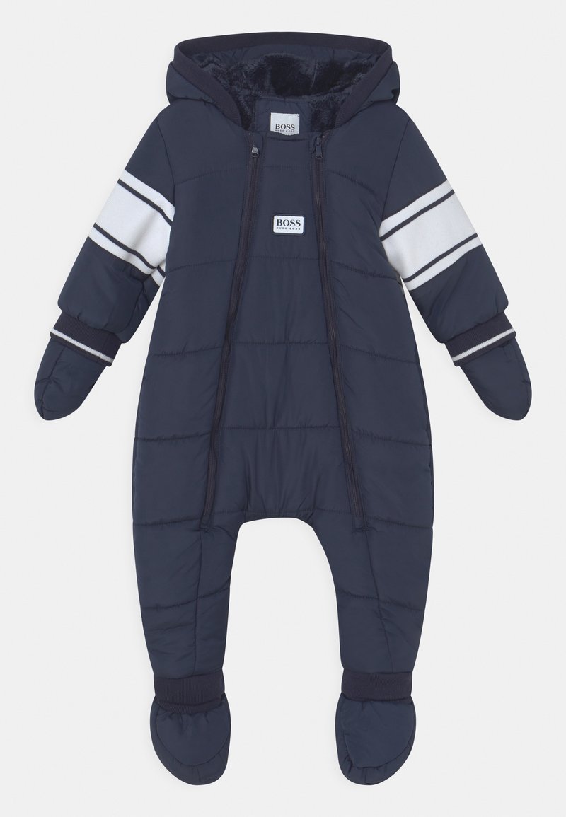 Combinaison d'hiver matelassée pour bébé en bleu marine avec capuche, moufles et chaussons intégrés, détail de rayure blanche sur les manches et fermetures éclair frontales.