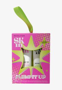 Jasnoróżowe pudełko z zieloną wstążką, zawierające dwie białe tubki oznaczone "Plump-Tide Soothing Moisturiser" oraz "Peptide Pout Plumping Lip Treatment."