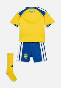 Κίτρινη και μπλε ποδοσφαιρική στολή Σουηδίας με κοντομάνικη φανέλα, ριγέ σορτσάκια και αντίστοιχες κίτρινες κάλτσες, τοποθετημένη επίπεδα σε λευκό φόντο.