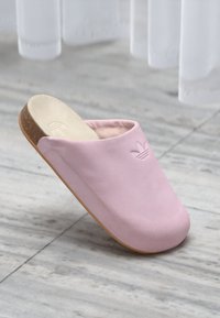 Ροζ παντόφλα με λείο επάνω μέρος και στρογγυλή μύτη, με επίπεδη σόλα από φελλό και ανάγλυφο λογότυπο μπροστά.