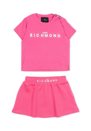 Roze tweedelig kinderoutfit met een top met korte mouwen en een rok, beide met het witte "John Richmond"-logo bedrukt.
